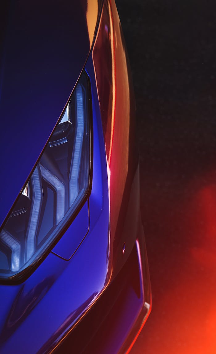 Vibrant close-up of a luxury sports car headlight featuring lens flare and reflections.